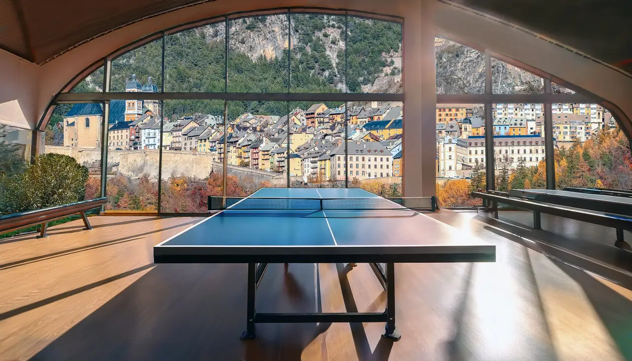 Table de tennis de table face aux fenêtres du gymnase, avec vue sur la vieille ville de Briançon